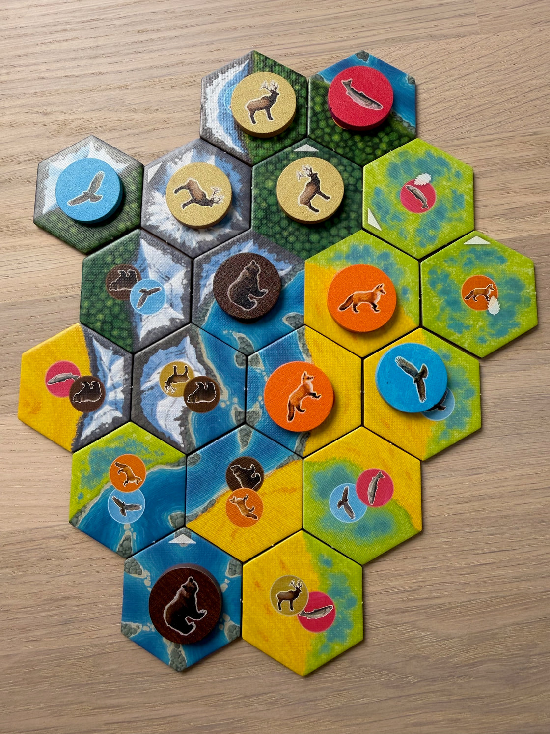 Ett färdigbyggt landskap i Cascadia sett uppifrån, med trädjur placerade på sexkantiga brickor av skog, flod, berg och äng.